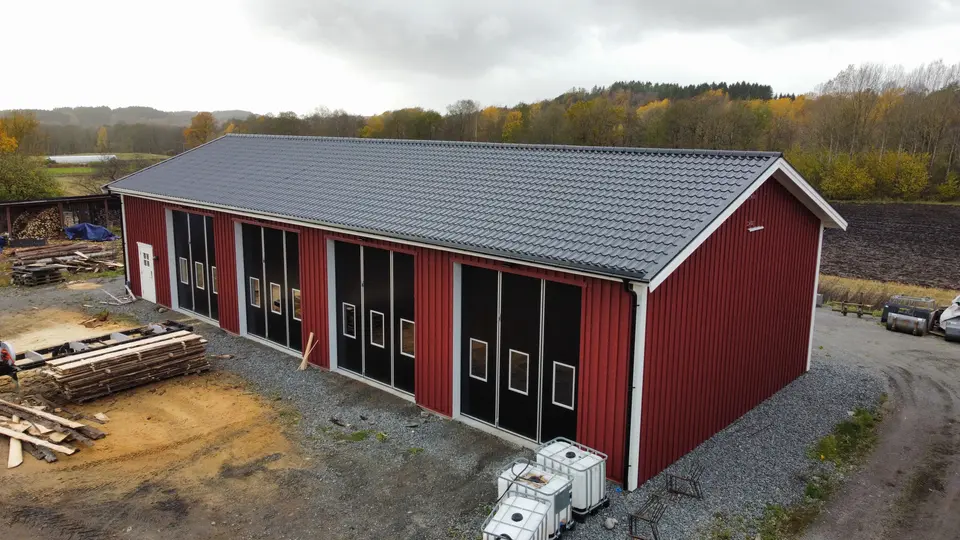 Röd träklädd hall med grått tak och flera svarta portar — KAAB Bygg